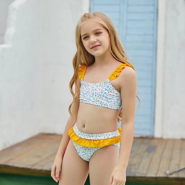 Charming 10 year old girl in swimsuit, hat with sunscreen among tropical  green leaves on white background Stock Photo